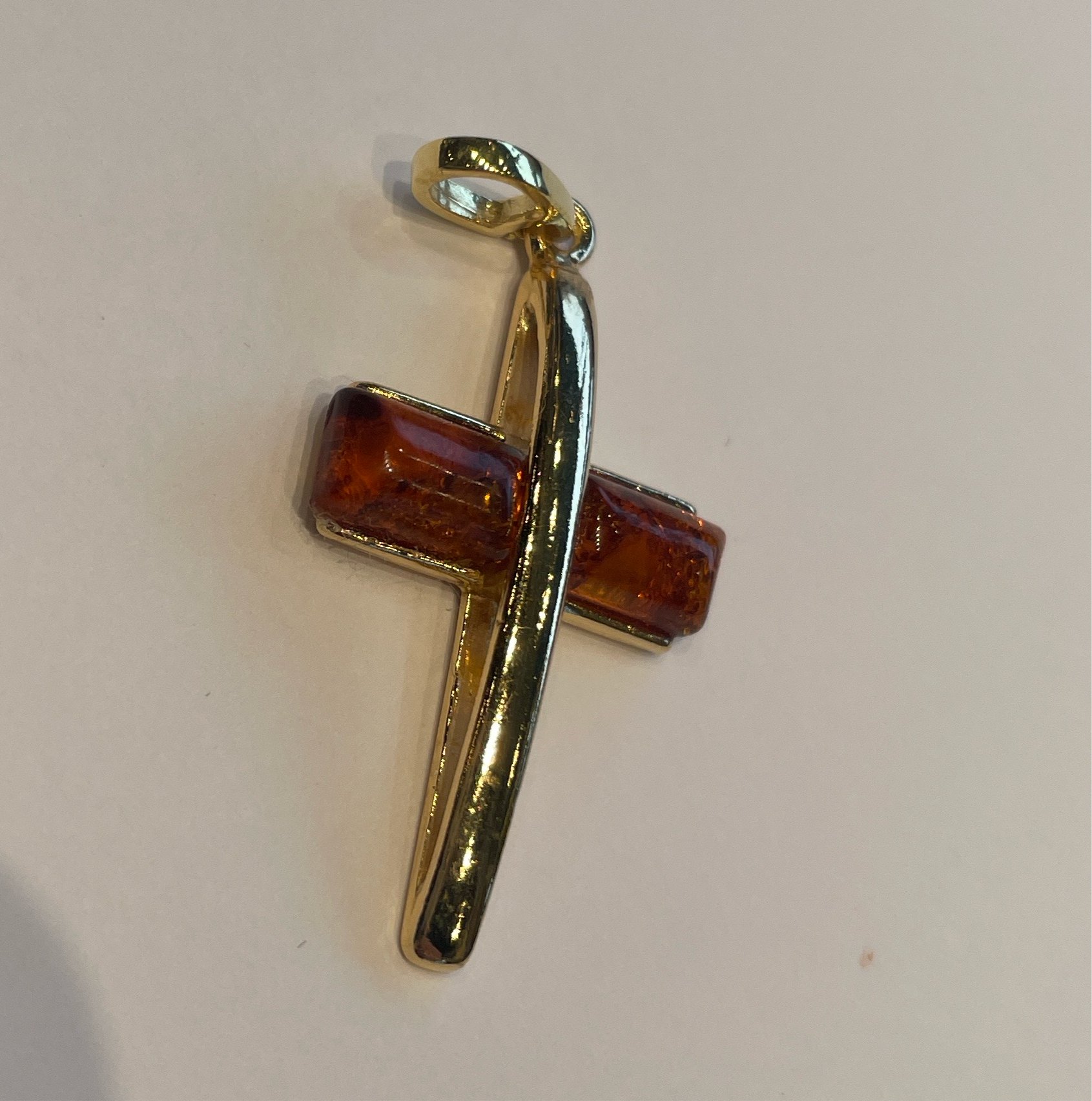 A gold plated silver and amber cross in cognac color