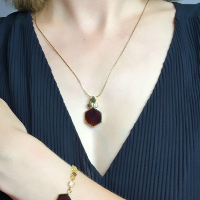 An elegant cherry amber pendant on a long chain with a shiny zircon