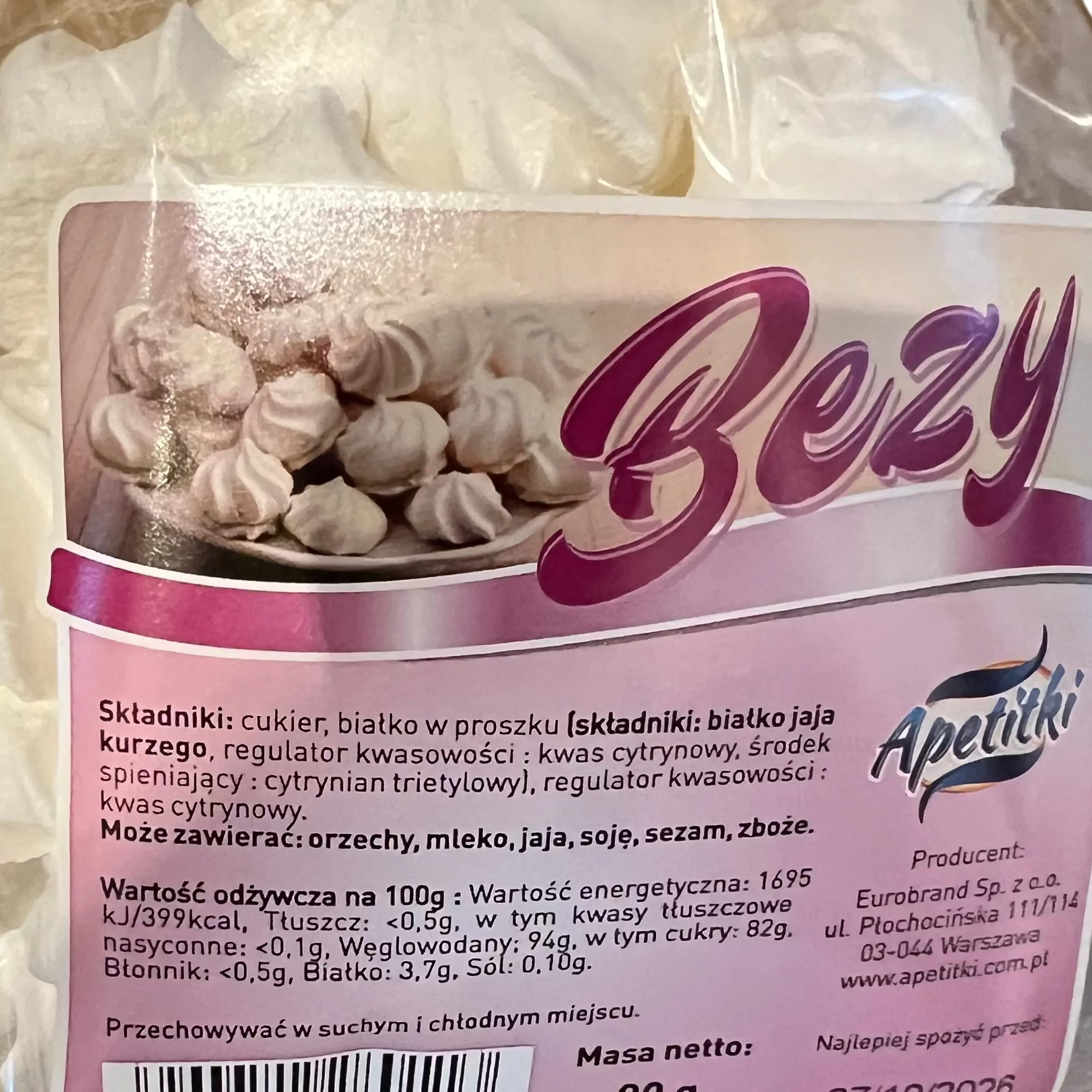 Packaged white meringues with a purple label on a metallic surface