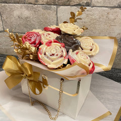 Bouquet of cookies shaped like flowers in a decorative box with gold accents on a stone surface.
