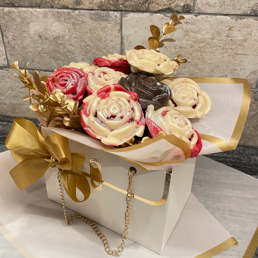 Bouquet of cookies shaped like flowers in a decorative box with gold accents on a stone surface.