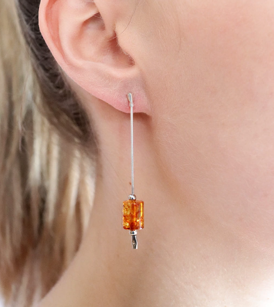Delicate hanging silver earrings with cognac Baltic amber in the shape of a cylinder