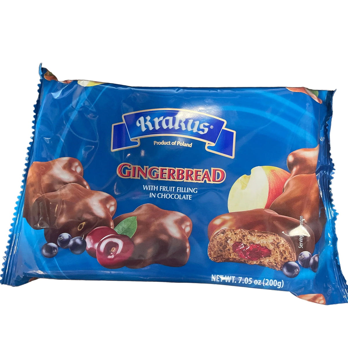 A package of Kirkus Gingerbread cookies with fruit bling in chocolate, placed on a dark wooden tabletop. The packaging is bright blue with illustrations of chocolate-covered gingerbread cookies, cherries, blueberries, and an apple slice.