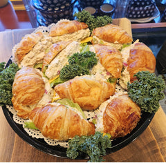 Salad with croissants and greens on a black plate