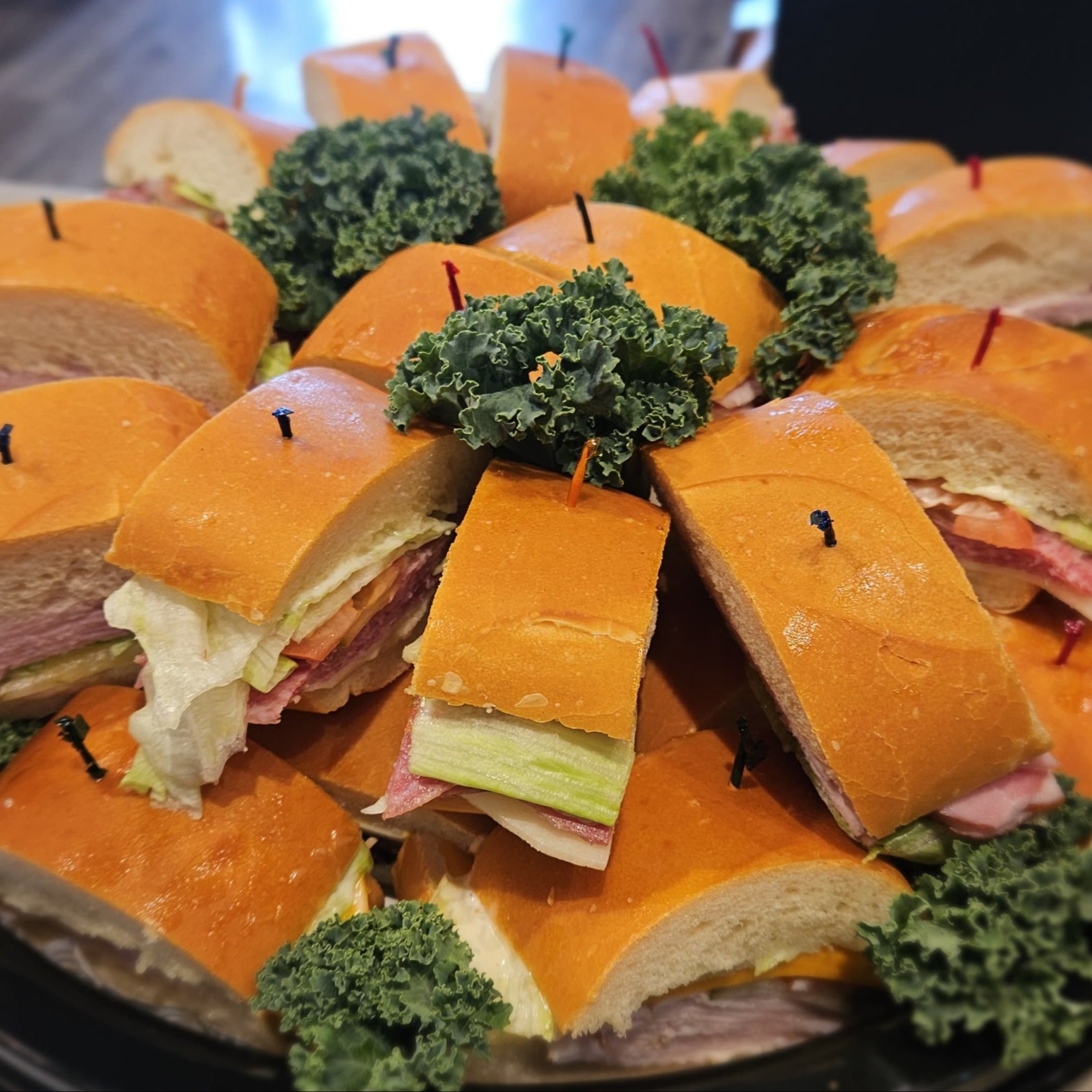 Platter of sub sandwiches with lettuce garnish on a white surface