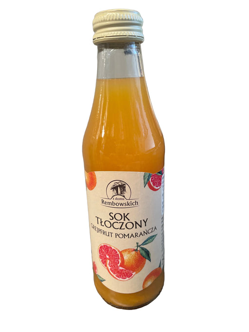 Bottle of Sok Zony grapefruit orange juice on a gray surface with a blurred background.