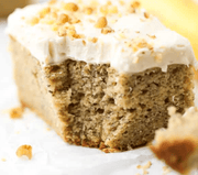 Slice of banana cake with cream cheese frosting on a white plate